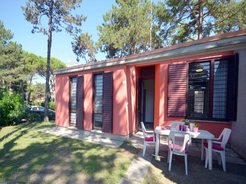 ein rosa kleines Haus mit einem Tisch und Stühlen in der Unterkunft Villa Beethoven in Lignano Sabbiadoro