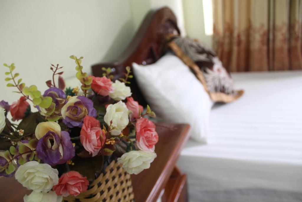 un jarrón de flores sobre una mesa con una almohada en Hotel Kien Nga, en Thach Loi