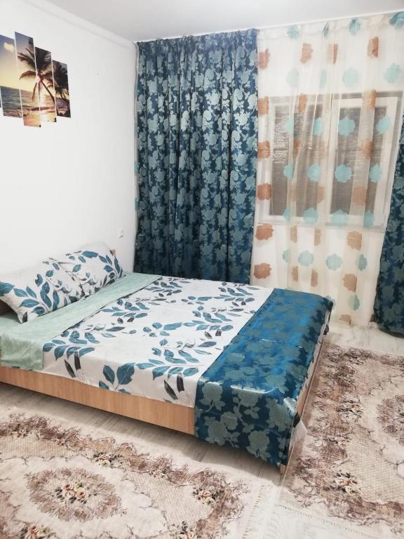 a bedroom with a bed with a blue comforter at Căsuța de vacanță in Năvodari