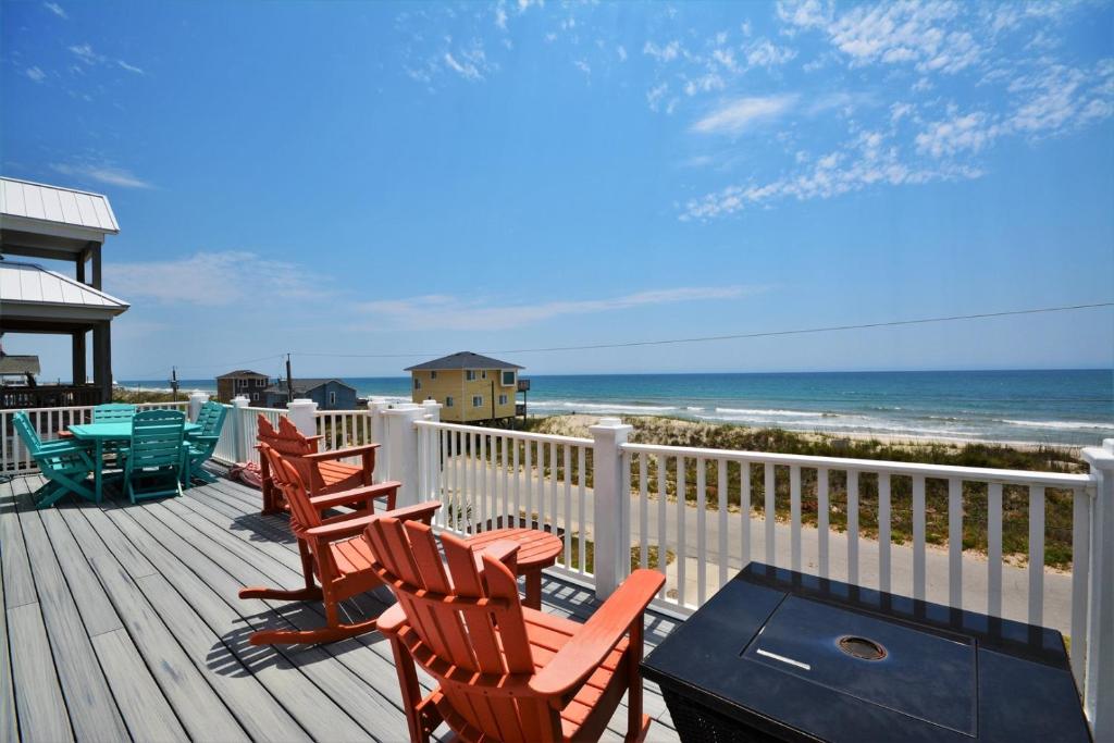 eine Terrasse mit Stühlen und einem Tisch und dem Meer in der Unterkunft Shore Blessed in North Topsail Beach