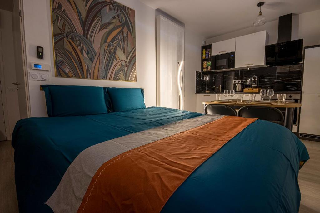 a bedroom with a blue bed and a kitchen at Studio cosy aux portes de Disney in Chessy