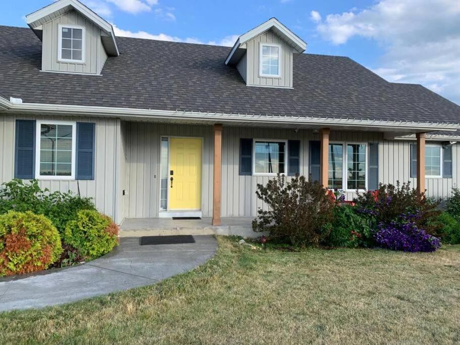 a house with a yellow door in a yard at Merlin Home With Amazing Lake Erie Views in Tilbury