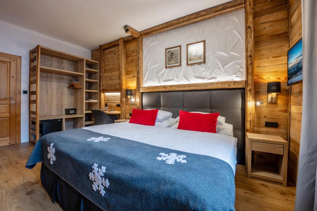 ein Schlafzimmer mit einem großen Bett mit roten Kissen in der Unterkunft Hotel Olympie in Špindlerův Mlýn