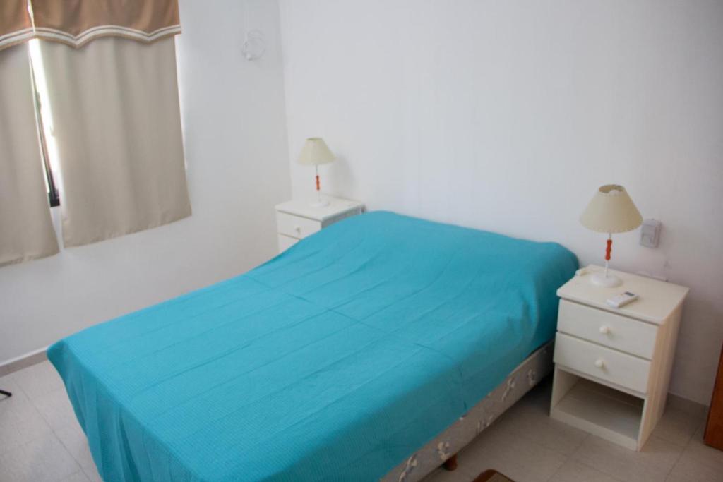 Un dormitorio con una cama azul y una mesita de noche. en VironasApartFederacion, en Federación