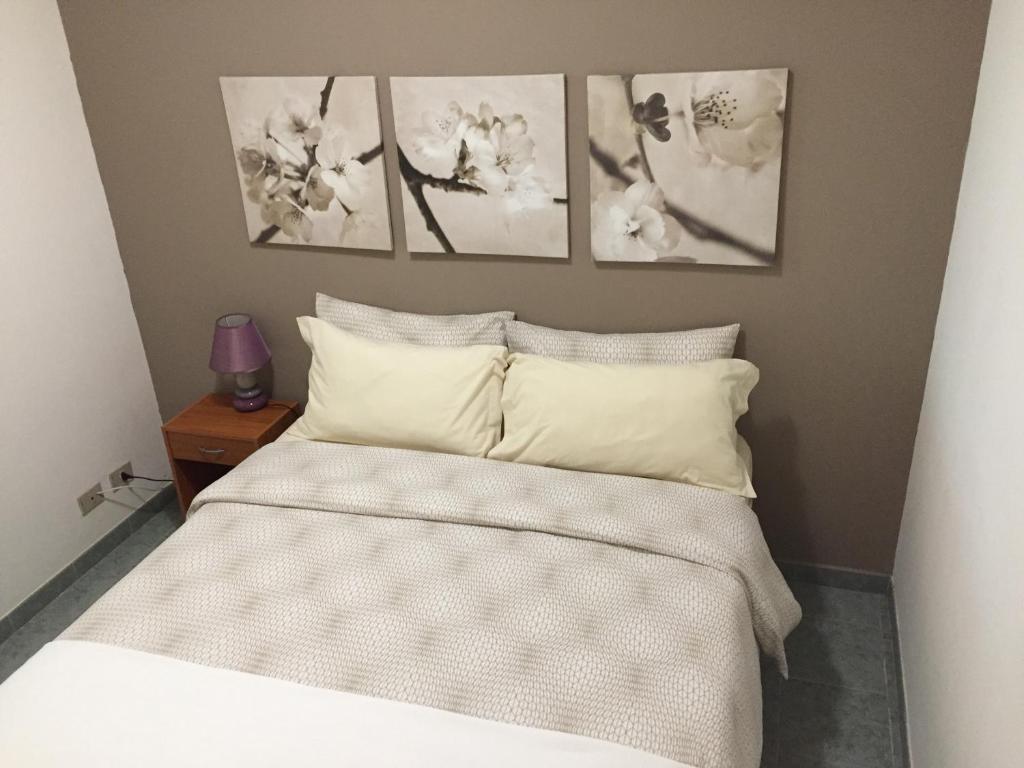 ein Schlafzimmer mit einem Bett mit vier Bildern an der Wand in der Unterkunft Appartamento Gna Turidda in Ragusa