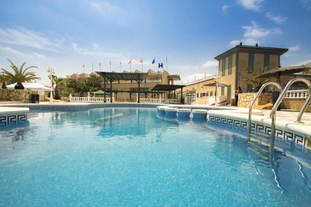 une grande piscine d'eau bleue devant un bâtiment dans l'établissement Hotel Costa Blanca Rojales, à Rojales