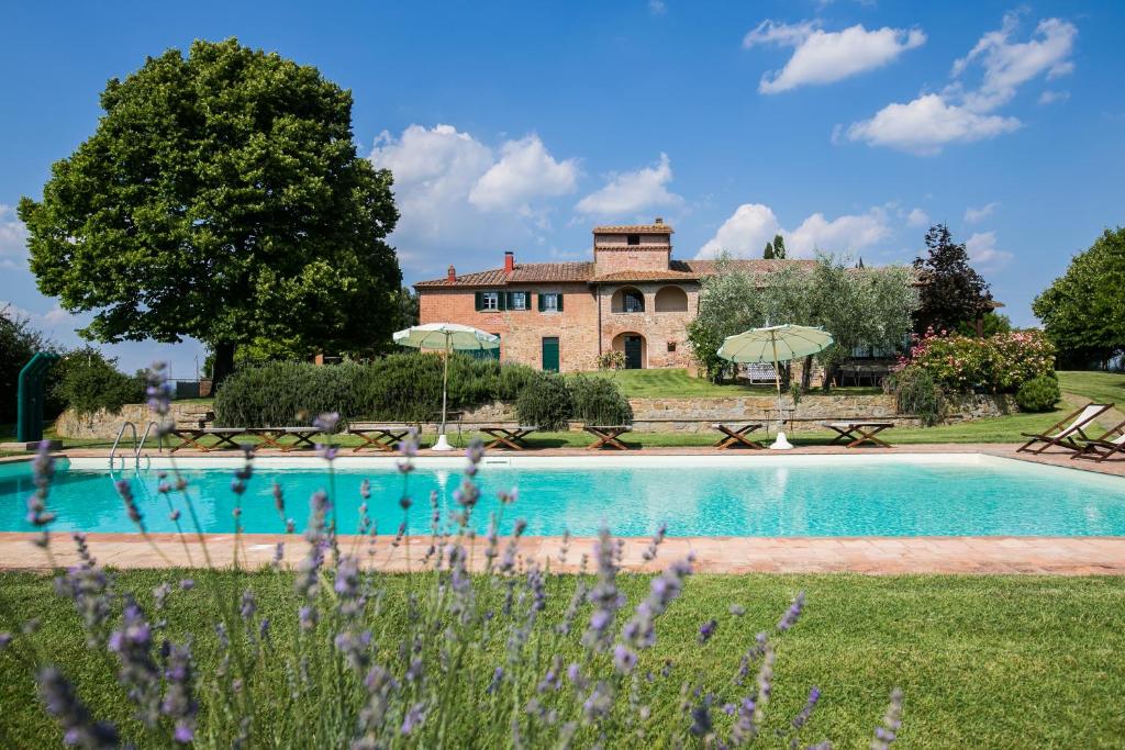 a swimming pool in front of a building with a house at Villa Borgonuovo in Cortona
