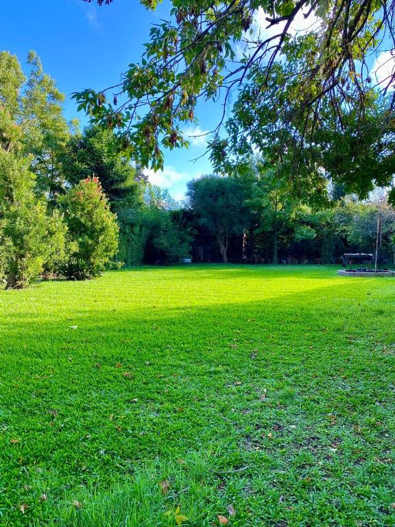 a field of green grass with a bench in the distance at Maravillosa Casa Quinta in Del Viso