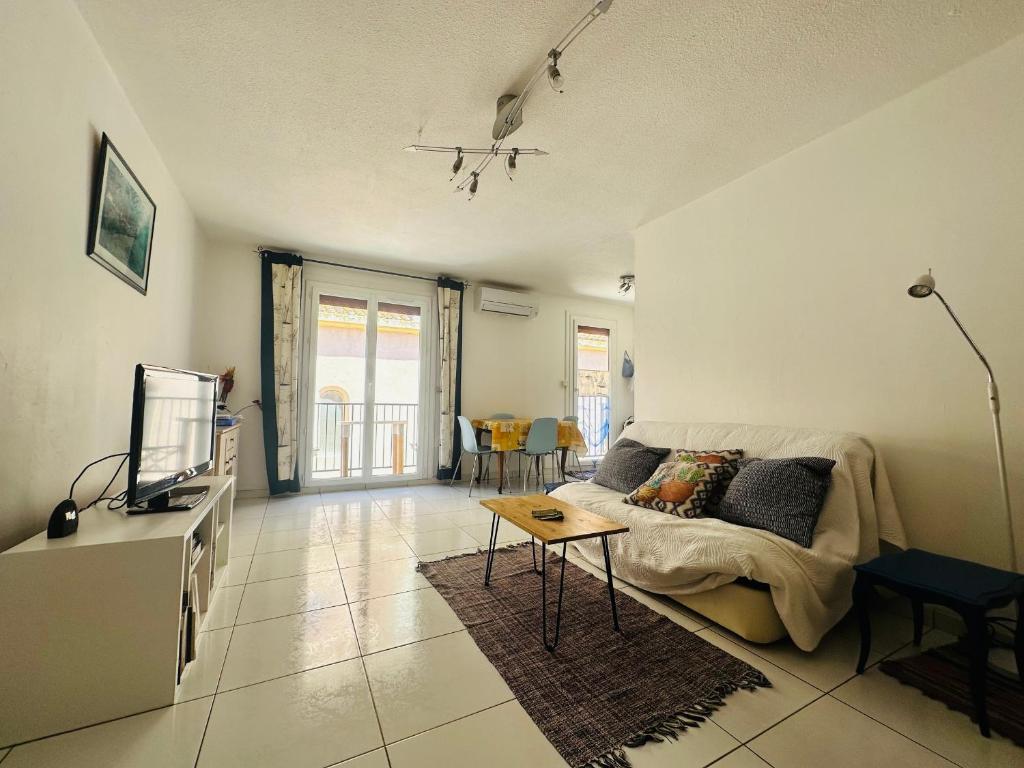 a living room with a couch and a tv at Port-Vendres - T2 climatisé, parking, WIFI - 3* - FR-1-309-388 in Port-Vendres