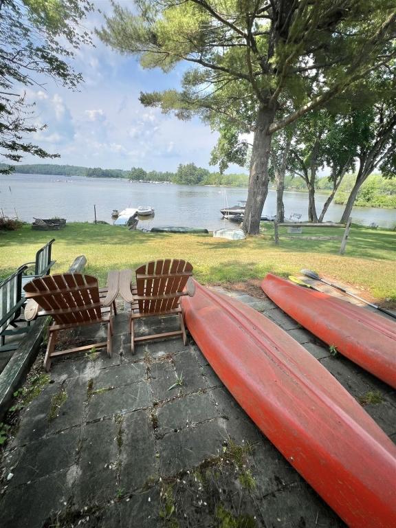 two kayaks and two chairs next to a lake at SEBAGO ESCAPE LIMIT 12 home in Raymond