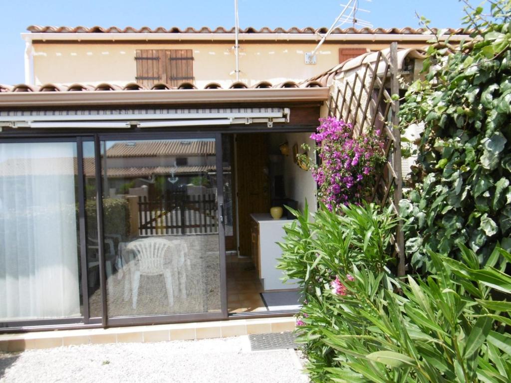 une maison avec une porte coulissante en verre avec une chaise blanche dans l'établissement Charmante villa T2 mezzanine avec cour, jardin, véranda, barbecue et parking privé, proche plage et commerces - FR-1-797-2, à Port-la-Nouvelle