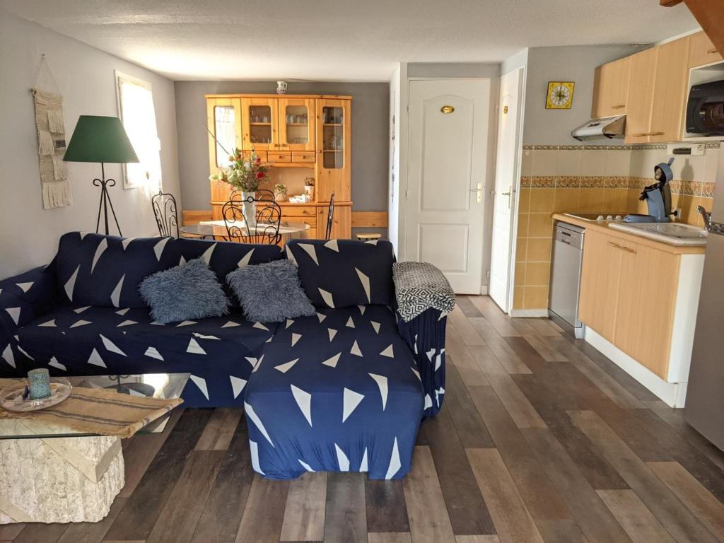 un salon avec un canapé bleu et une cuisine dans l'établissement Belle villa climatisée T3 avec mezzanine, jardin arboré, garage et à 900m de la plage, 6/7 personnes - FR-1-797-36, à Port-la-Nouvelle