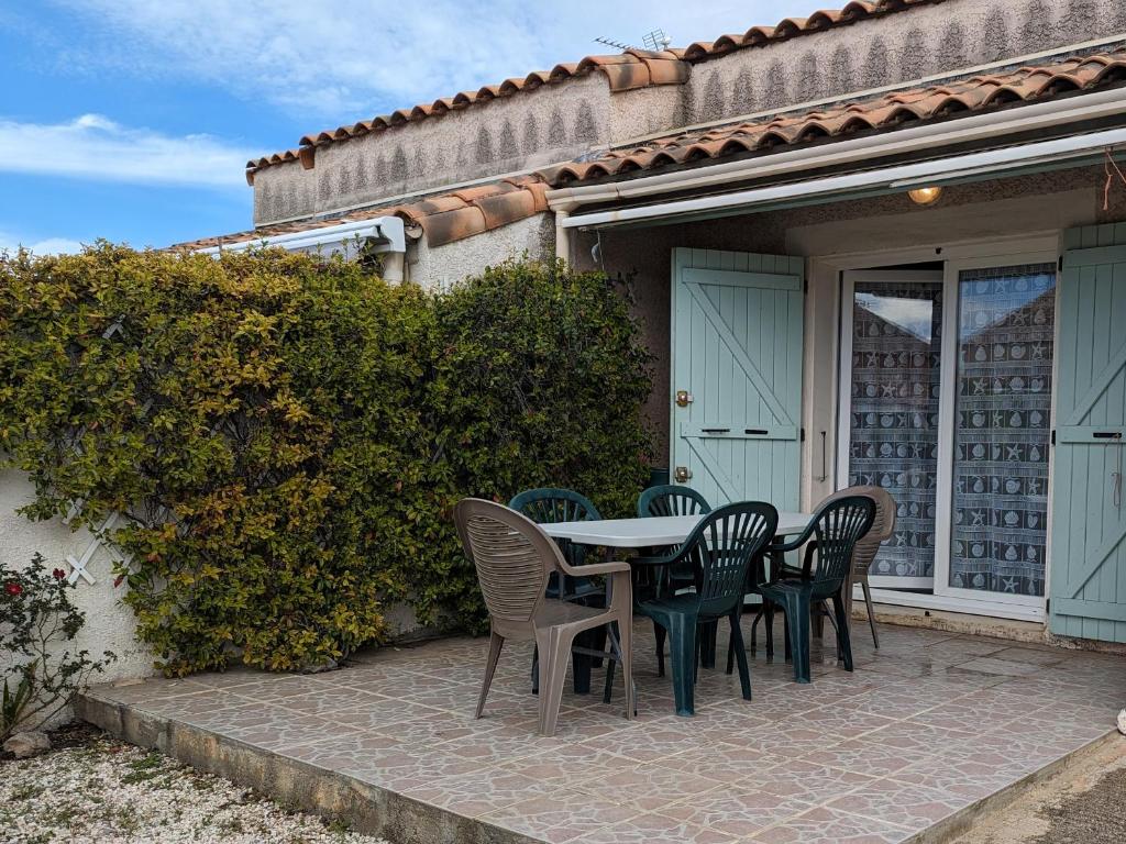 - une table et des chaises sur une terrasse à l'extérieur de la maison dans l'établissement Charmante Villa T3 Climatisée Proche Plage - Confort et Calme pour 6 Pers. - FR-1-797-21, à Port-la-Nouvelle