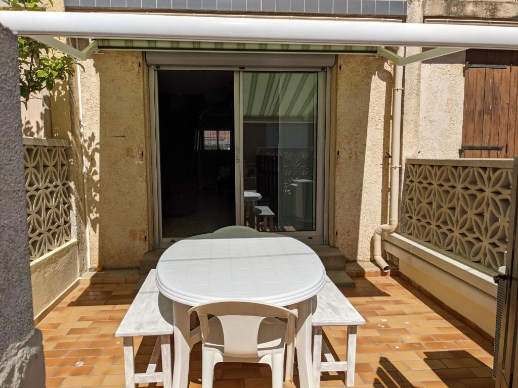 une table blanche et des chaises sur une terrasse dans l'établissement Villa T3 climatisée, 57m², 5/6 pers, proche plage, rénovée, terrasse, parking, quartier animé - FR-1-797-48, à Port-la-Nouvelle