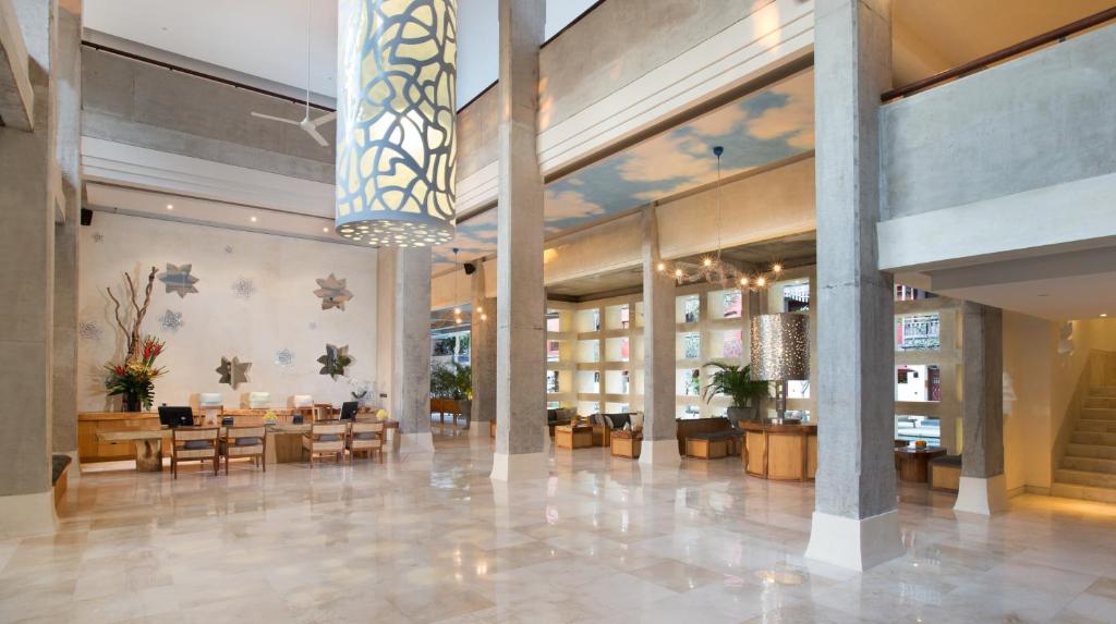 a lobby of a hotel with tables and chairs at Amnaya Resort Kuta in Kuta
