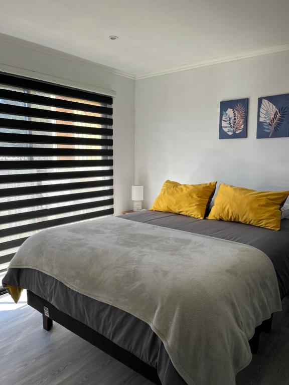 a bedroom with a large bed with yellow pillows at COSTA LOBO ll in Pichilemu