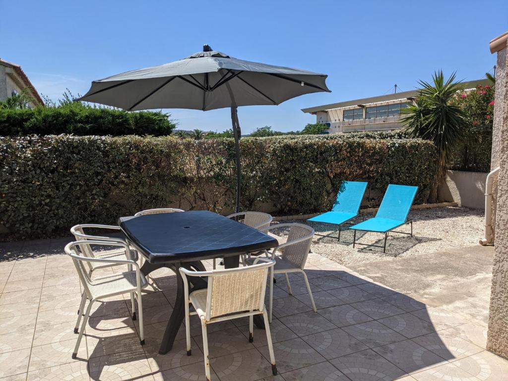 une table et des chaises avec un parasol sur une terrasse dans l'établissement Villa T3 Mezzanine à Port-la-Nouvelle: 6 pers, Terrasse, Proche Plage et Commerces, Confort Optimal. - FR-1-797-52, à Port-la-Nouvelle