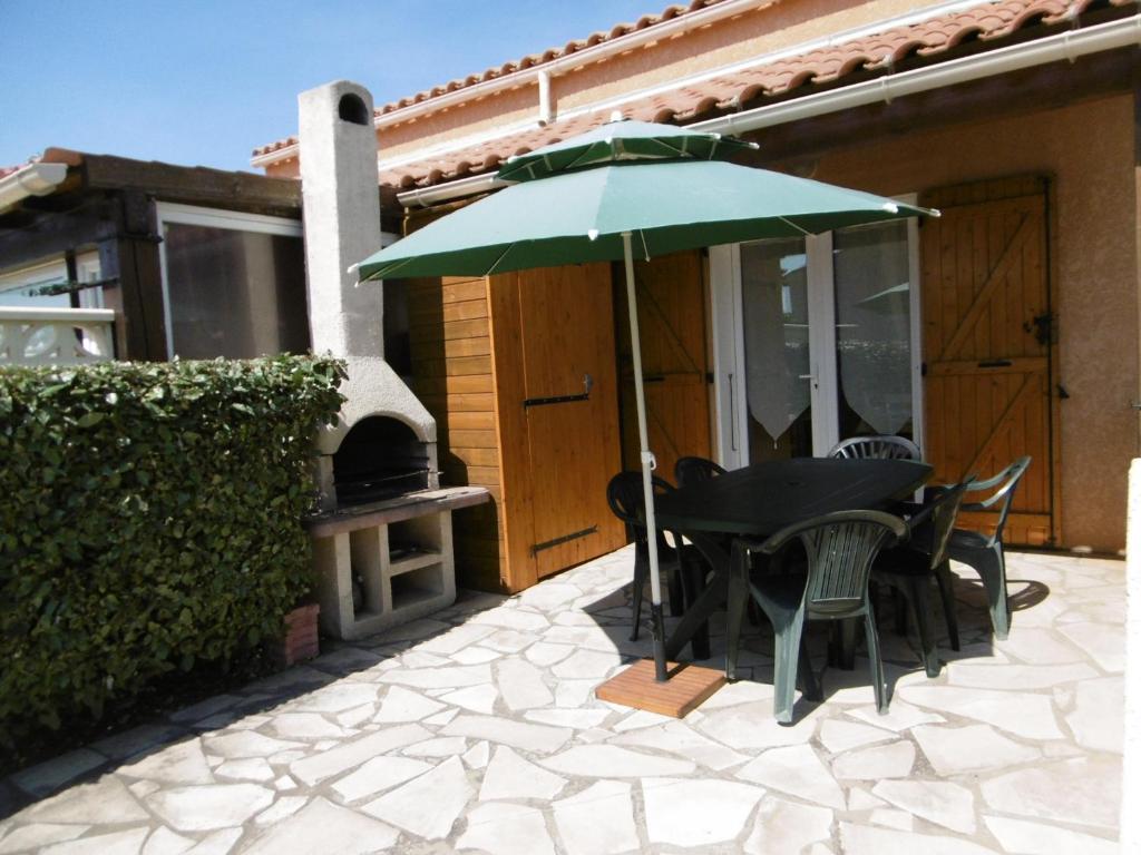 - une table et des chaises sous un parasol sur la terrasse dans l'établissement Maison T3 cosy avec terrasse et parking, proche plage - 6 pers, entièrement équipée, secteur calme - FR-1-797-54, à Port-la-Nouvelle