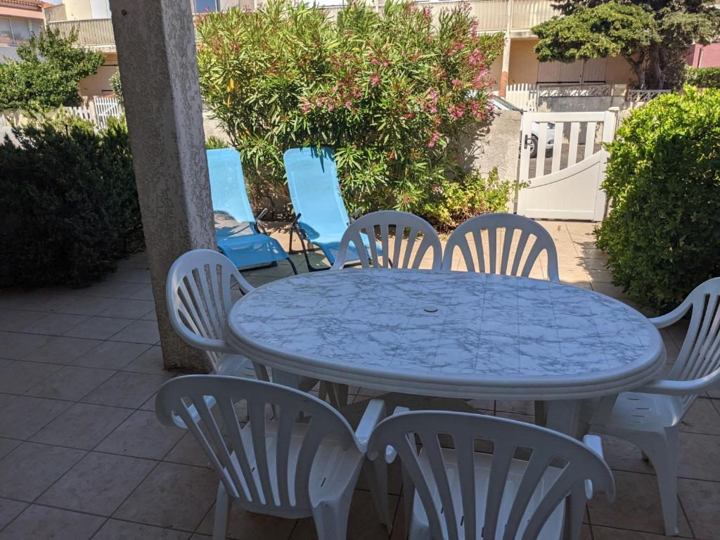- une table bleue et des chaises blanches sur la terrasse dans l'établissement Maison T4 avec garage, clim, cour arborée, confort total – 6 Pers, à 200m de la plage - FR-1-797-55, à Port-la-Nouvelle