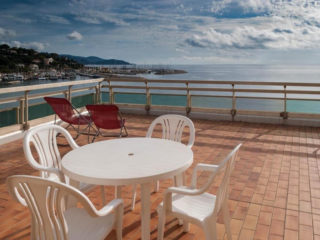 une table blanche et des chaises sur un balcon avec l'océan dans l'établissement Studio cabine au Lavandou avec terrasse vue mer et parking privé, proche plage et commerces - FR-1-803-41, au Lavandou