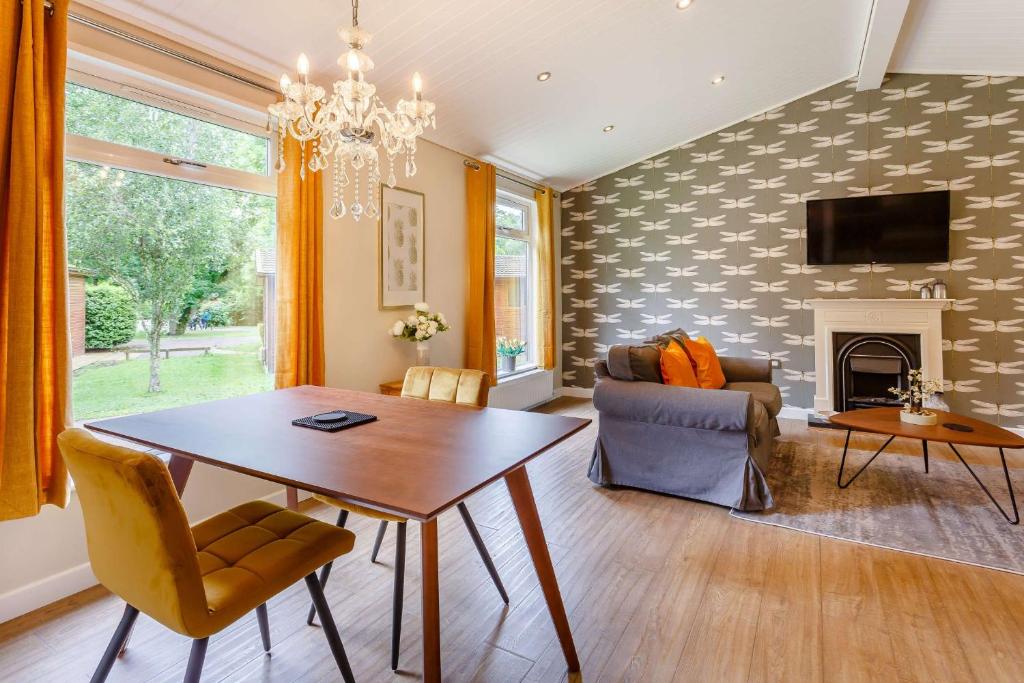 a living room with a table and a fireplace at Cupid's Lodge in Kingham