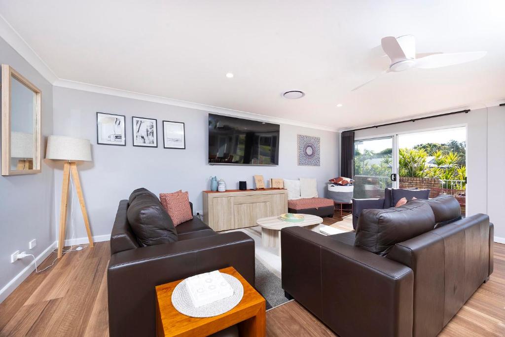 a living room with two leather couches and a table at Magpie Rest in Forster
