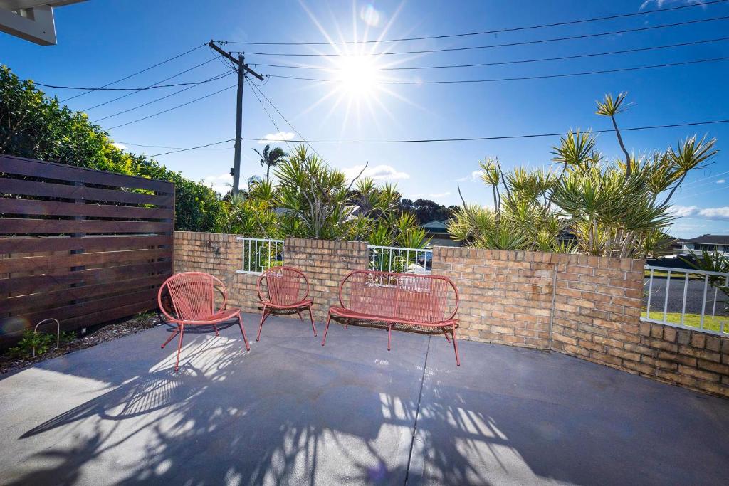 three red chairs sitting in front of a brick wall at Magpie Rest in Forster