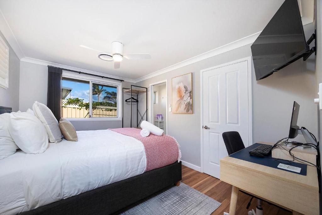 a bedroom with a bed and a desk with a computer at Magpie Rest in Forster