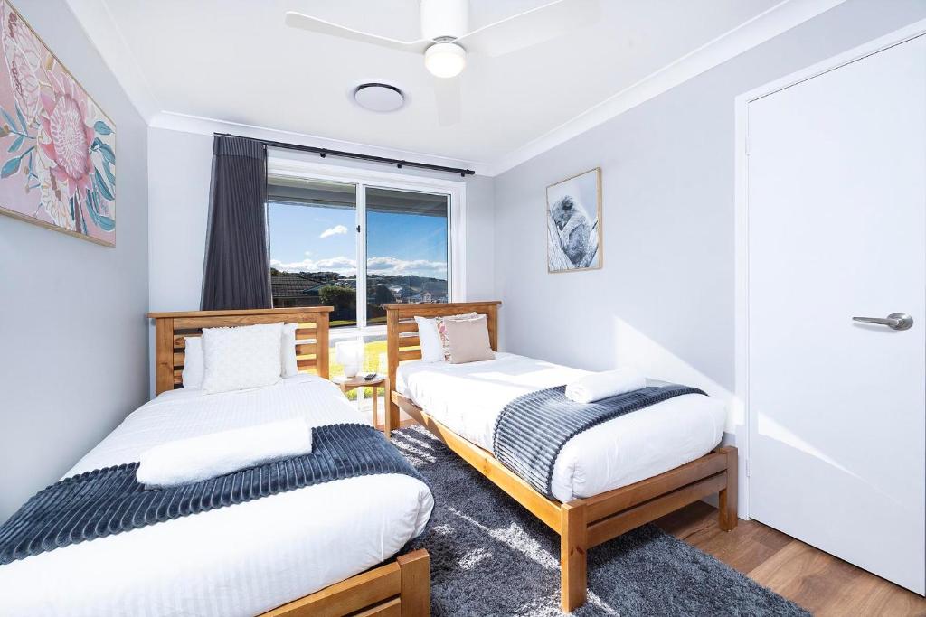 two beds in a room with a window at Magpie Rest in Forster