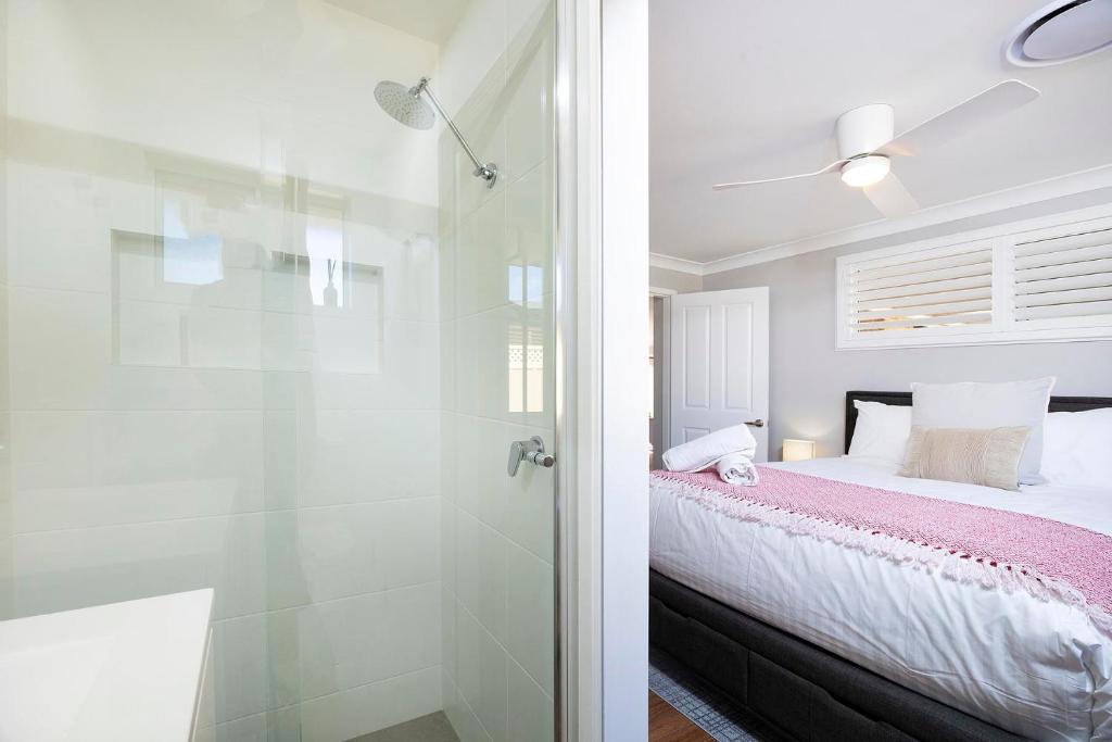 a bedroom with a bed and a glass shower at Magpie Rest in Forster