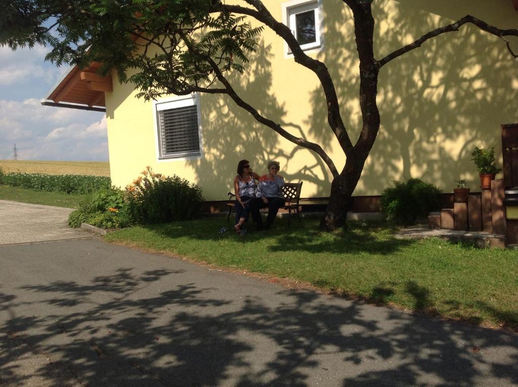 two women sitting on a bench under a tree at Beerenthal in Karnberg