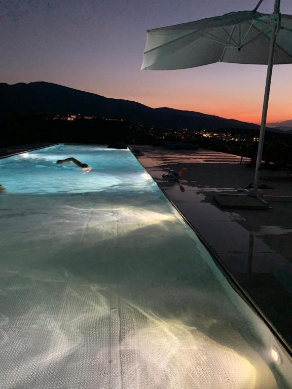 a swimming pool with an umbrella and people in the water at Villa Pirello in Guardiagrele