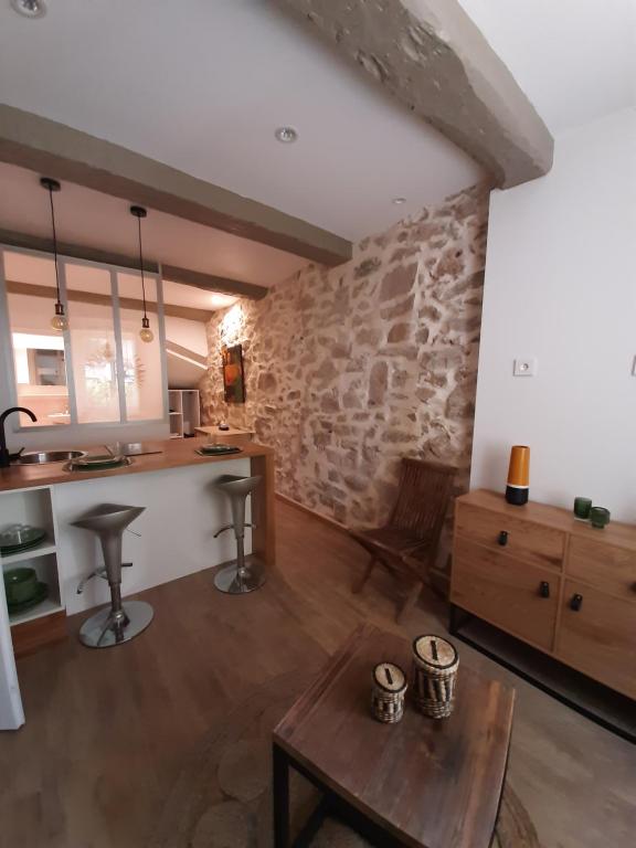 un salon avec une table et un mur en pierre dans l'établissement Coup de cœur pour amoureux en vadrouille, au Muy