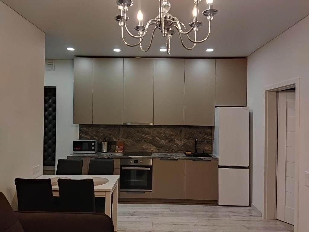 a kitchen with a table and a white refrigerator at Aušros Alėjos Apartamentai in Šiauliai