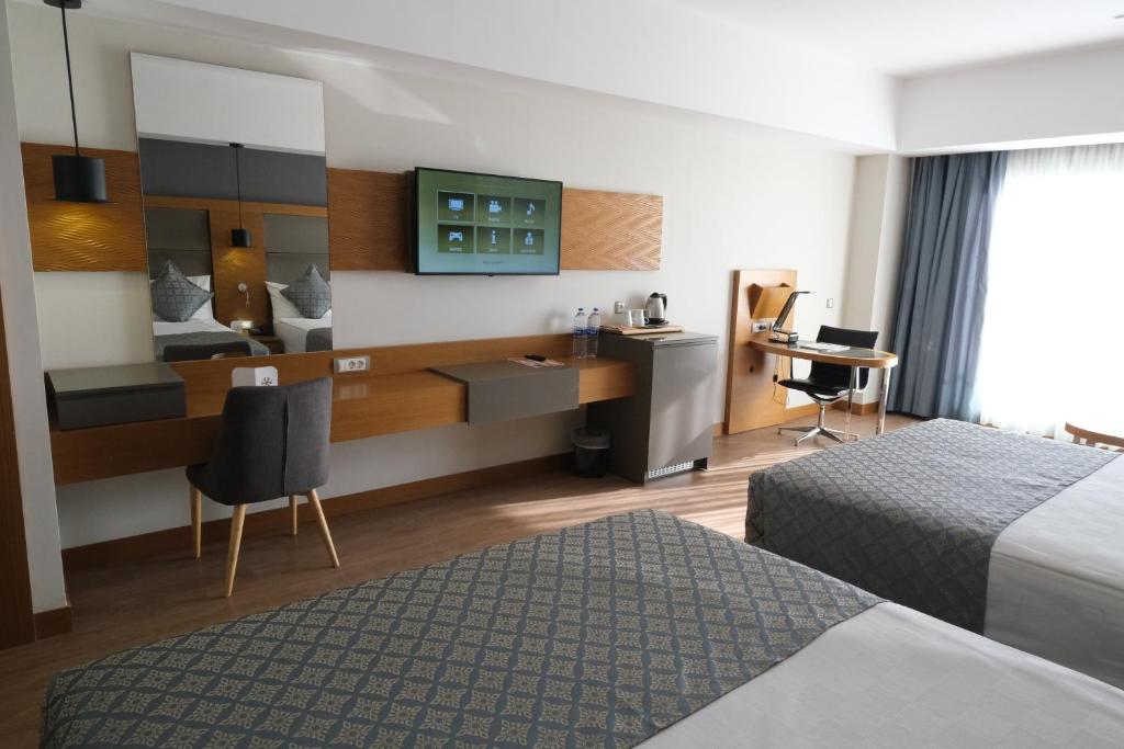a hotel room with two beds and a desk at Liberty Kuşadası in Kusadası