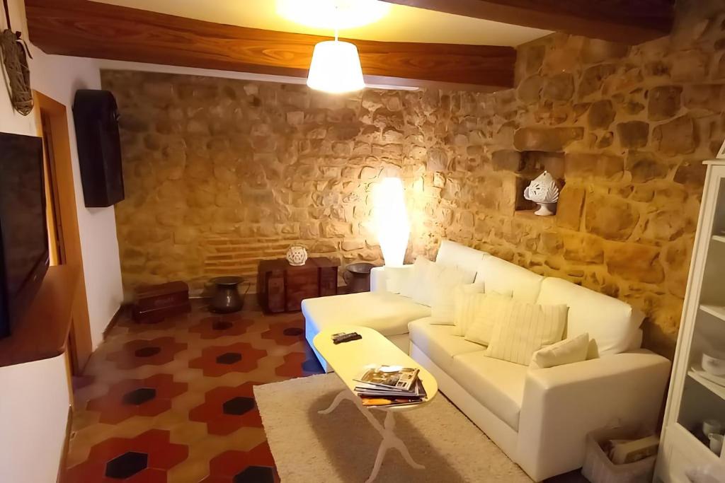 a living room with a white couch and a stone wall at Charme & Relax in Centro Storico in Gavorrano