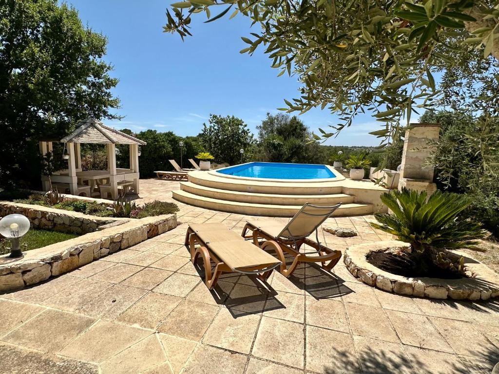 un patio avec deux chaises et une piscine dans l'établissement Il Giardino di Maria - Villa Exclusive Use, à Ostuni