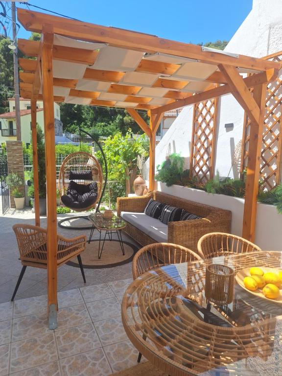 a patio with a wooden pergola and tables and chairs at Vithos in Agnontas