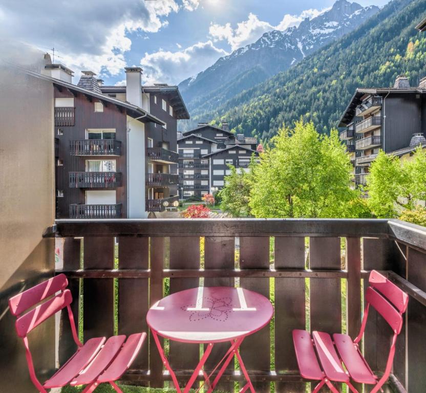 une table et des chaises roses sur un balcon avec des montagnes dans l'établissement Studio du Brévent - Welkeys, à Chamonix-Mont-Blanc