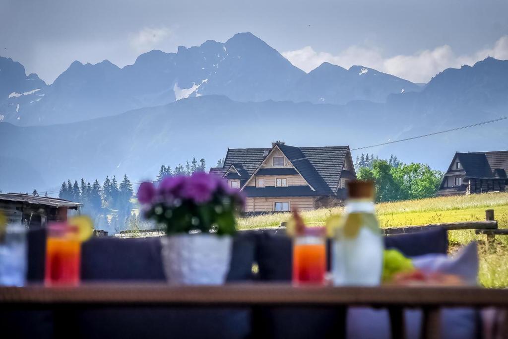 une table avec vue sur une maison et des montagnes dans l'établissement Osada Góralska Ostoja Pod Gubałówką z Jacuzzi, à Zakopane