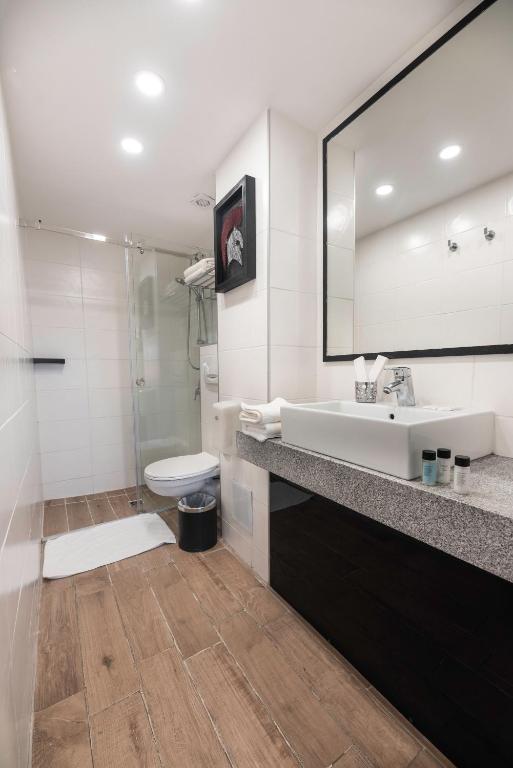 a bathroom with a sink and a toilet and a mirror at Rise Urban Art Hotel in Larnaca