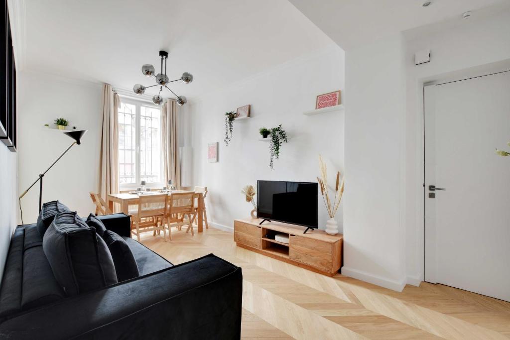 un salon avec un canapé noir et une télévision dans l'établissement Spacieux Appartement cosy -2BR 8P-Pl de la Nation, à Paris