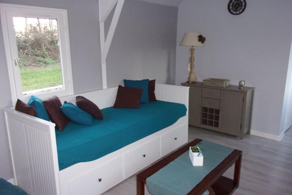 une chambre avec un lit avec des draps bleus et une fenêtre dans l'établissement Longère en bois à 15 min de la mer, à Bretteville-Saint-Laurent