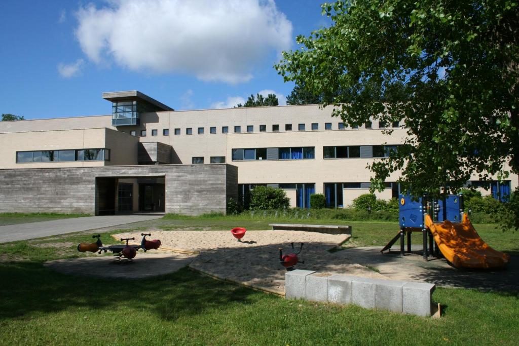 um edifício com um parque infantil em frente a um edifício em Jeugdherberg De Peerdevisser em Oostduinkerke