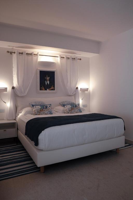 a white bedroom with a large white bed with two lamps at The White Knight Premium Boutique Hotel in Għajnsielem