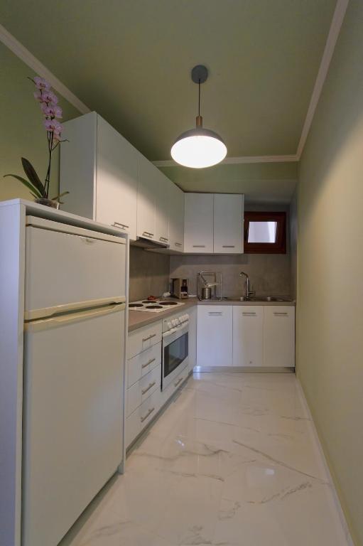 a kitchen with white cabinets and a white refrigerator at Parga Inn Suites in Parga