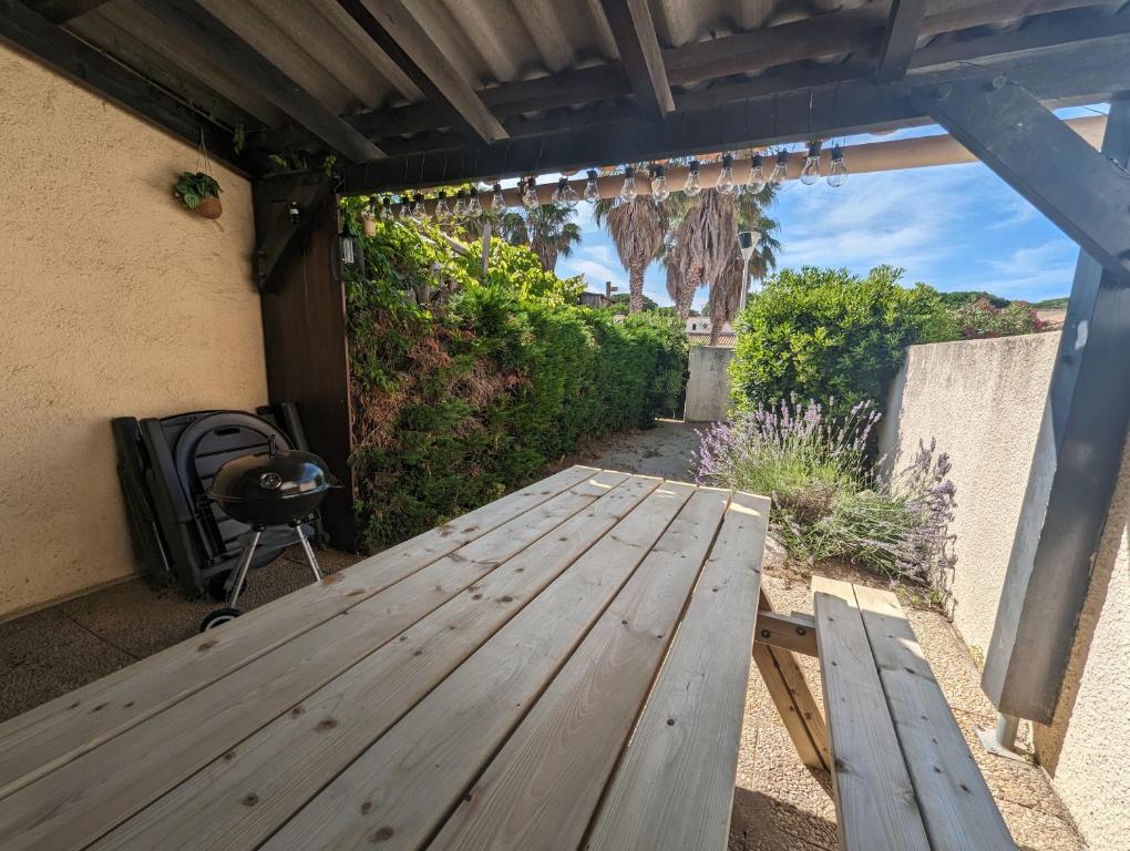 un tavolo da picnic in legno sul patio di una casa di Maison de vacances avec jardin, 650m de la mer, WIFI,CLIM a Saint-Cyprien