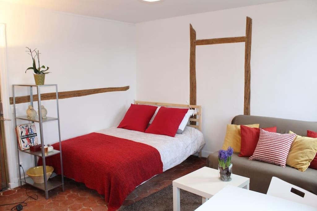 - une chambre avec un lit doté d'oreillers rouges et jaunes dans l'établissement Agréable studio à 1 min du Château de Versailles, à Versailles