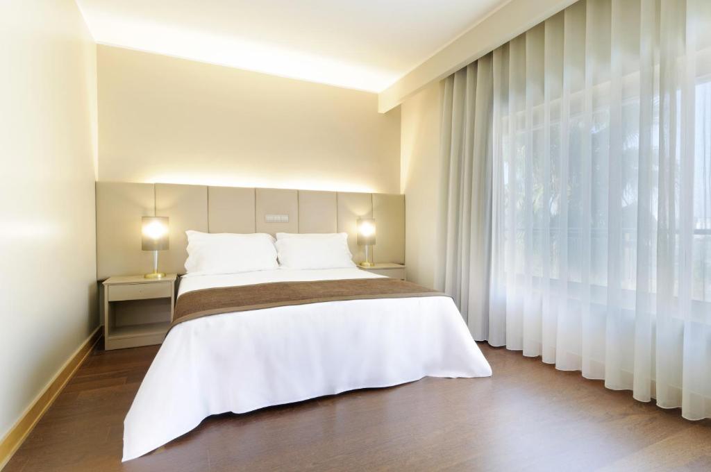 a bedroom with a large bed and a large window at TRYP by Wyndham Porto Expo Hotel in Leça da Palmeira