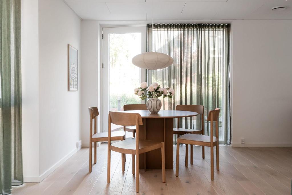 a dining room table with a vase of flowers on it at Beach Gardens 46 by Daniel&Jacob's in Copenhagen